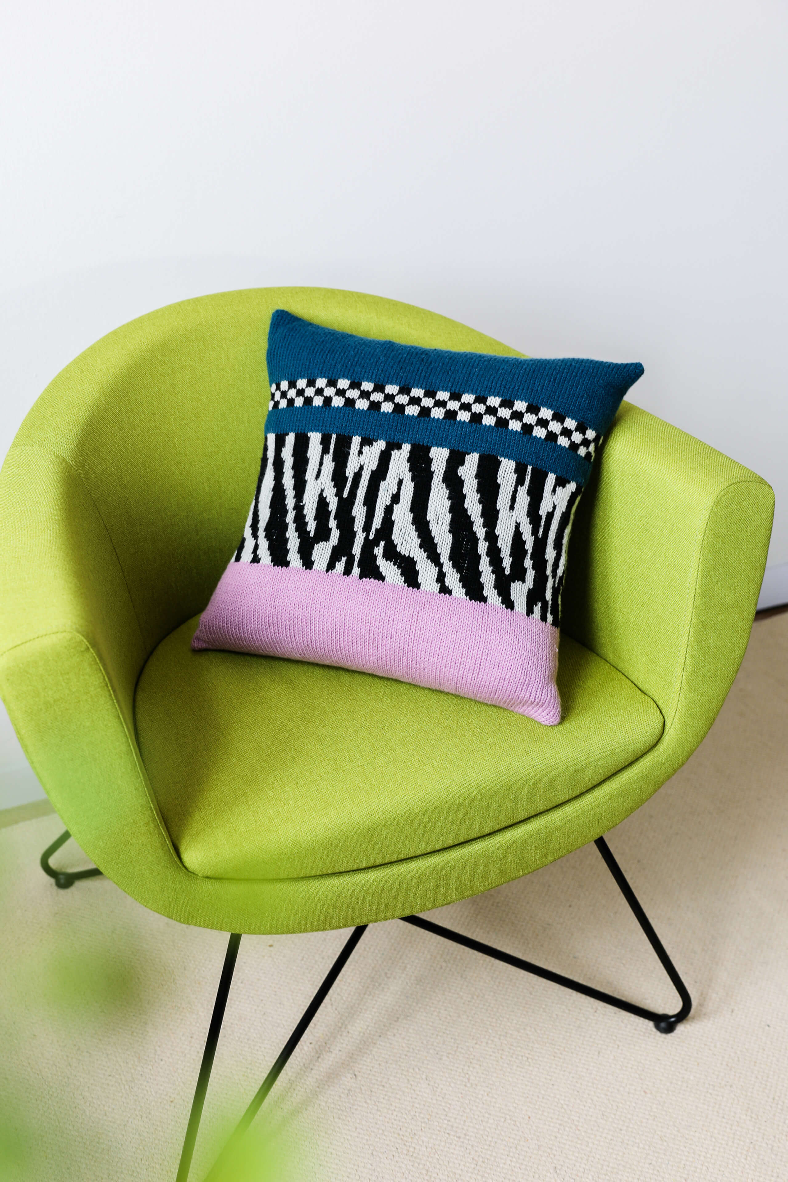 grüner Sessel mit buntem Kissen mit Zebraapplikation