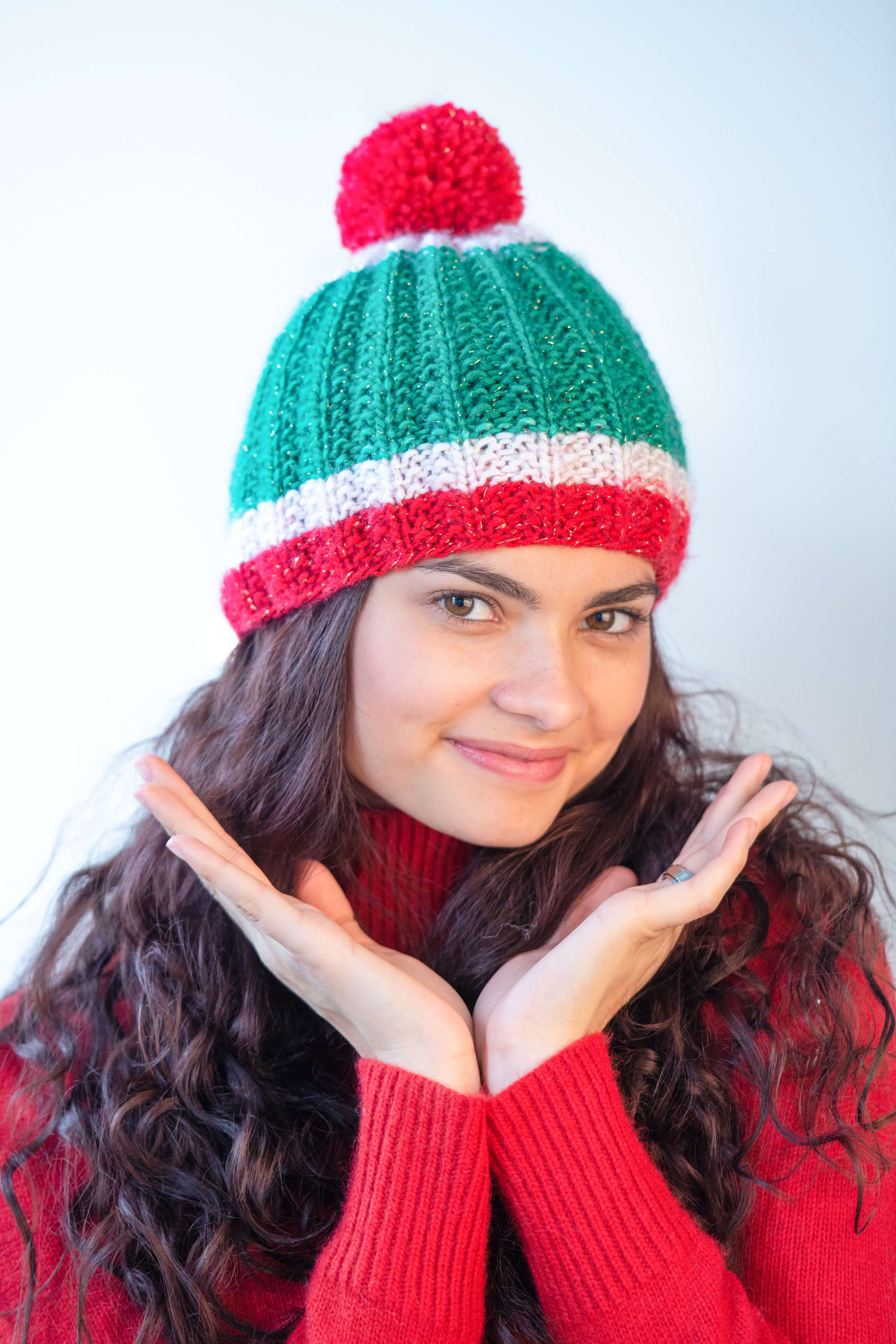 Frau in rotem Weihnachtspulli und grün-roter Bommelmütze