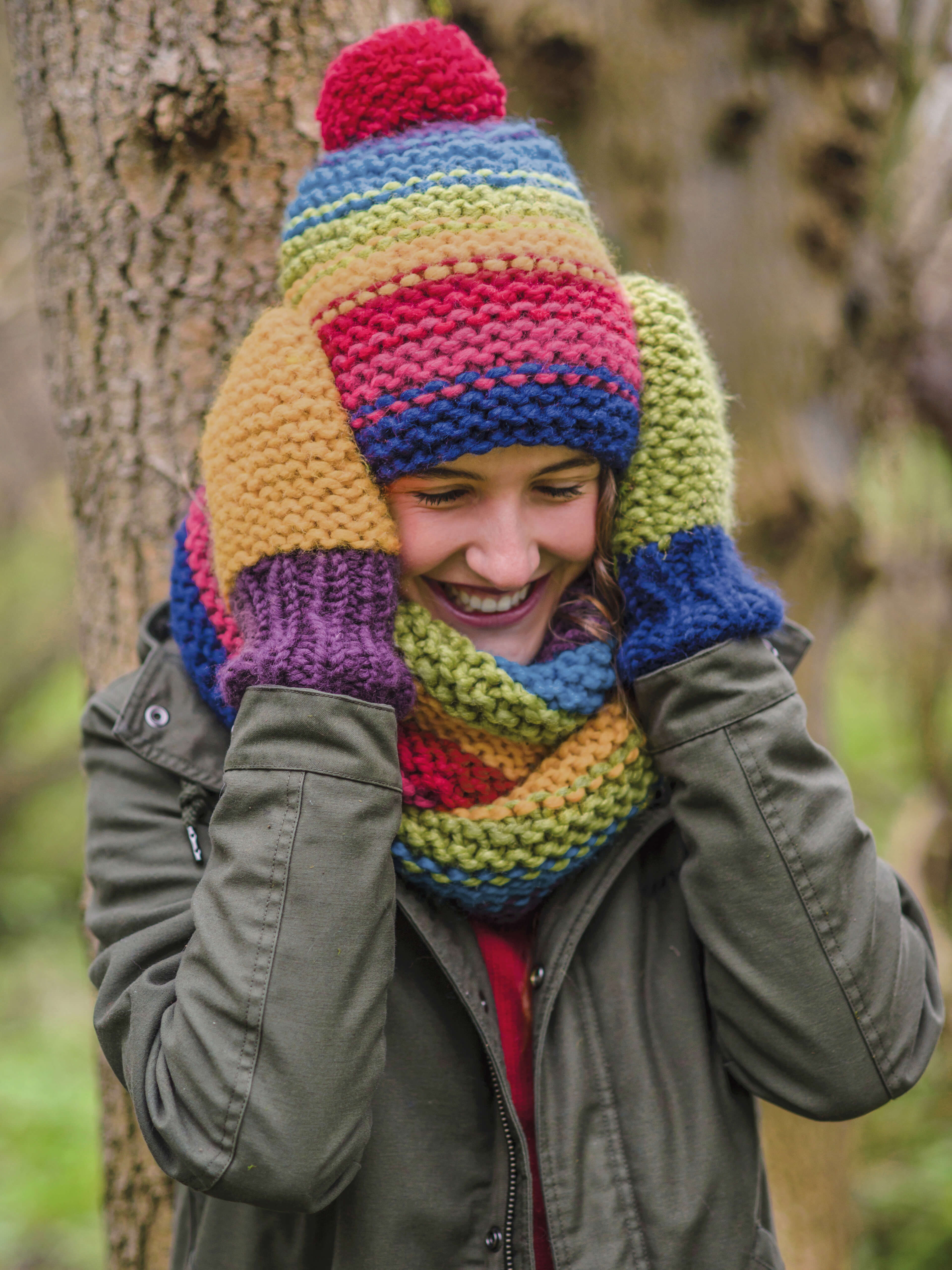 lachende Frau mit bunten zusammenpassenden Handschuhen, Mütze und Schal