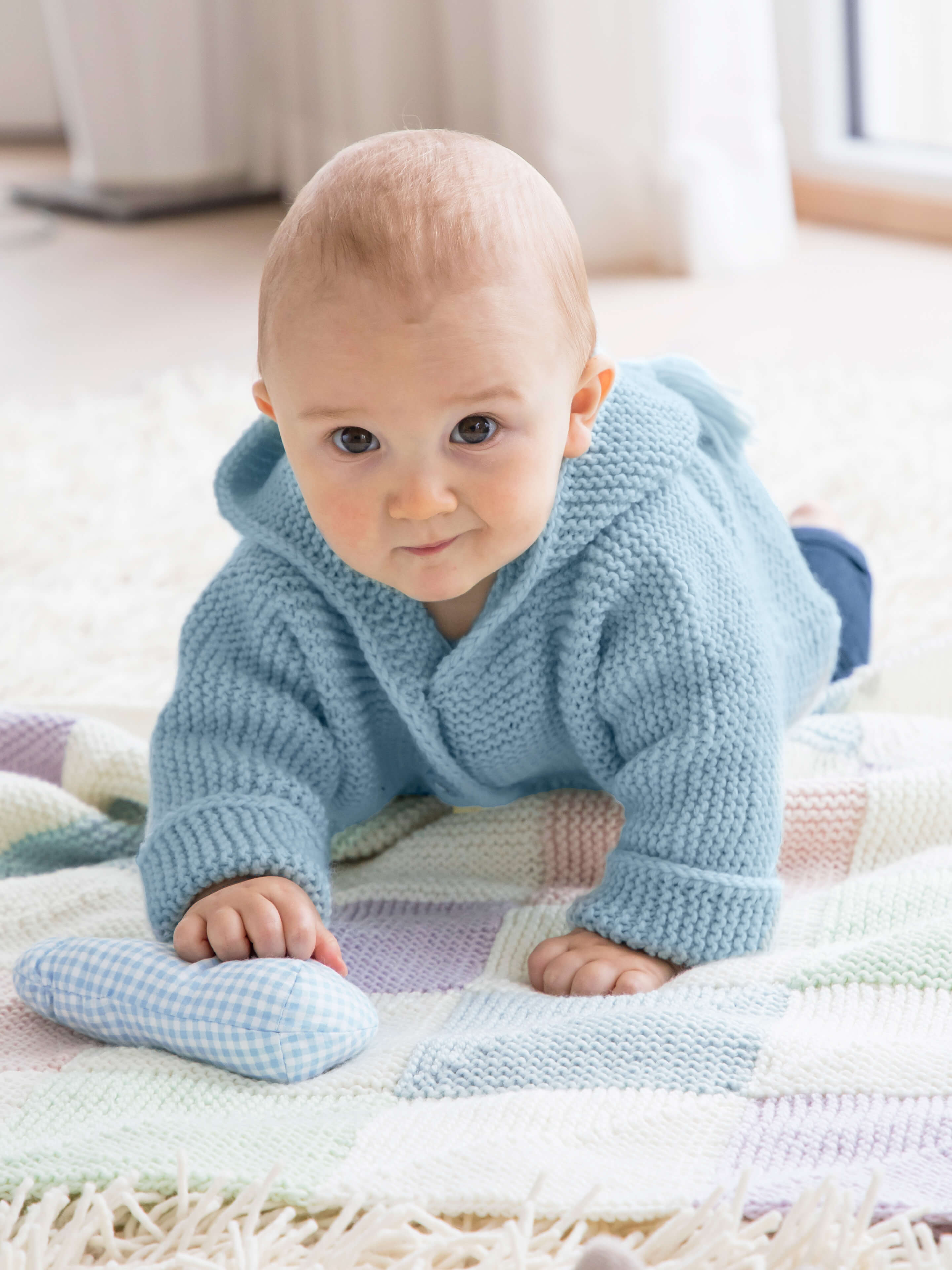 krabbelndes Baby in selbstgemachter Jacke auf einer selbstgestrickten Babydecke aus Baby Cashmere Wolle von Gründl