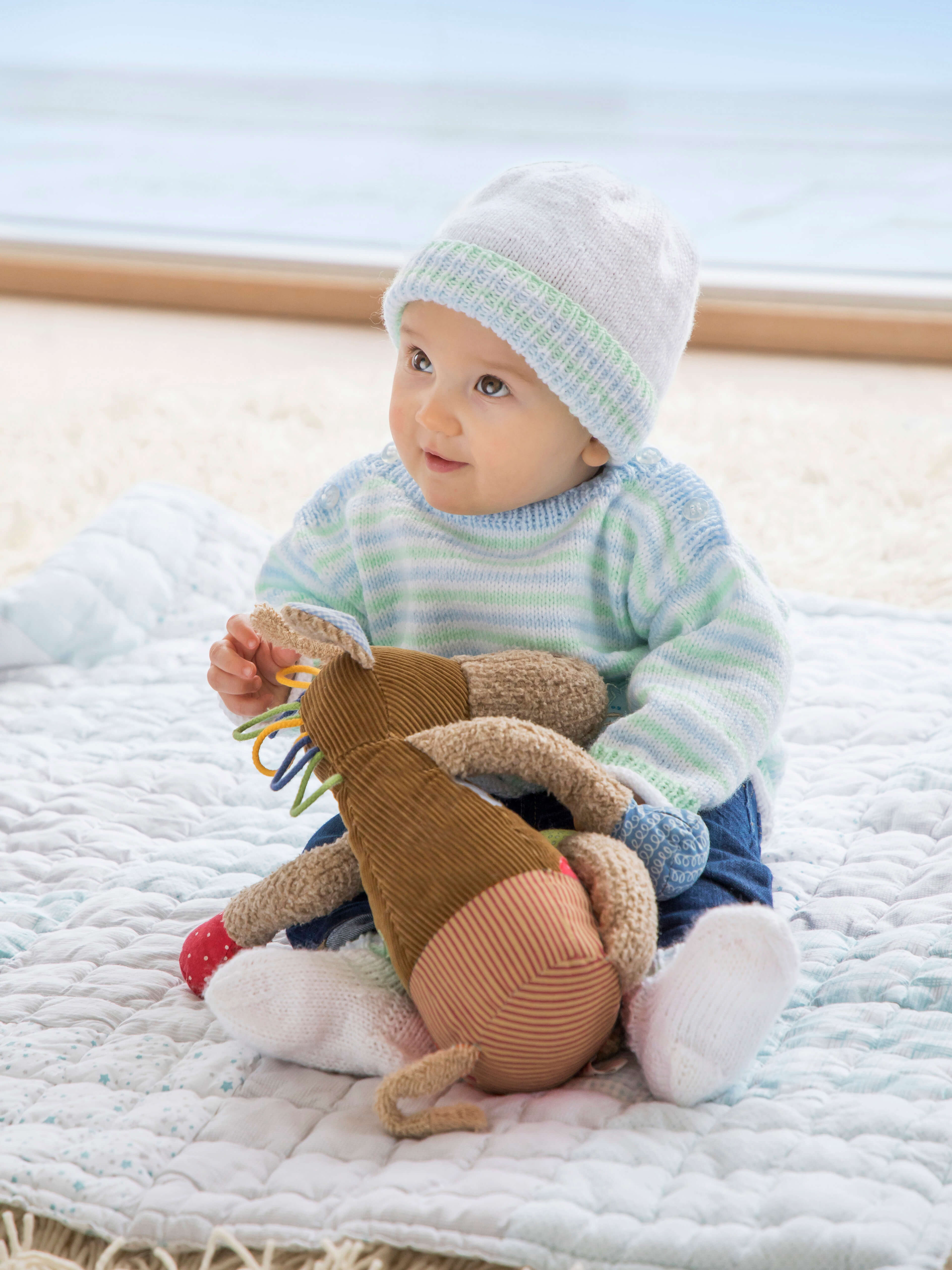 Baby in gestricktem Pullover mit passender Mütze aus Baby uni Wolle von Gründl