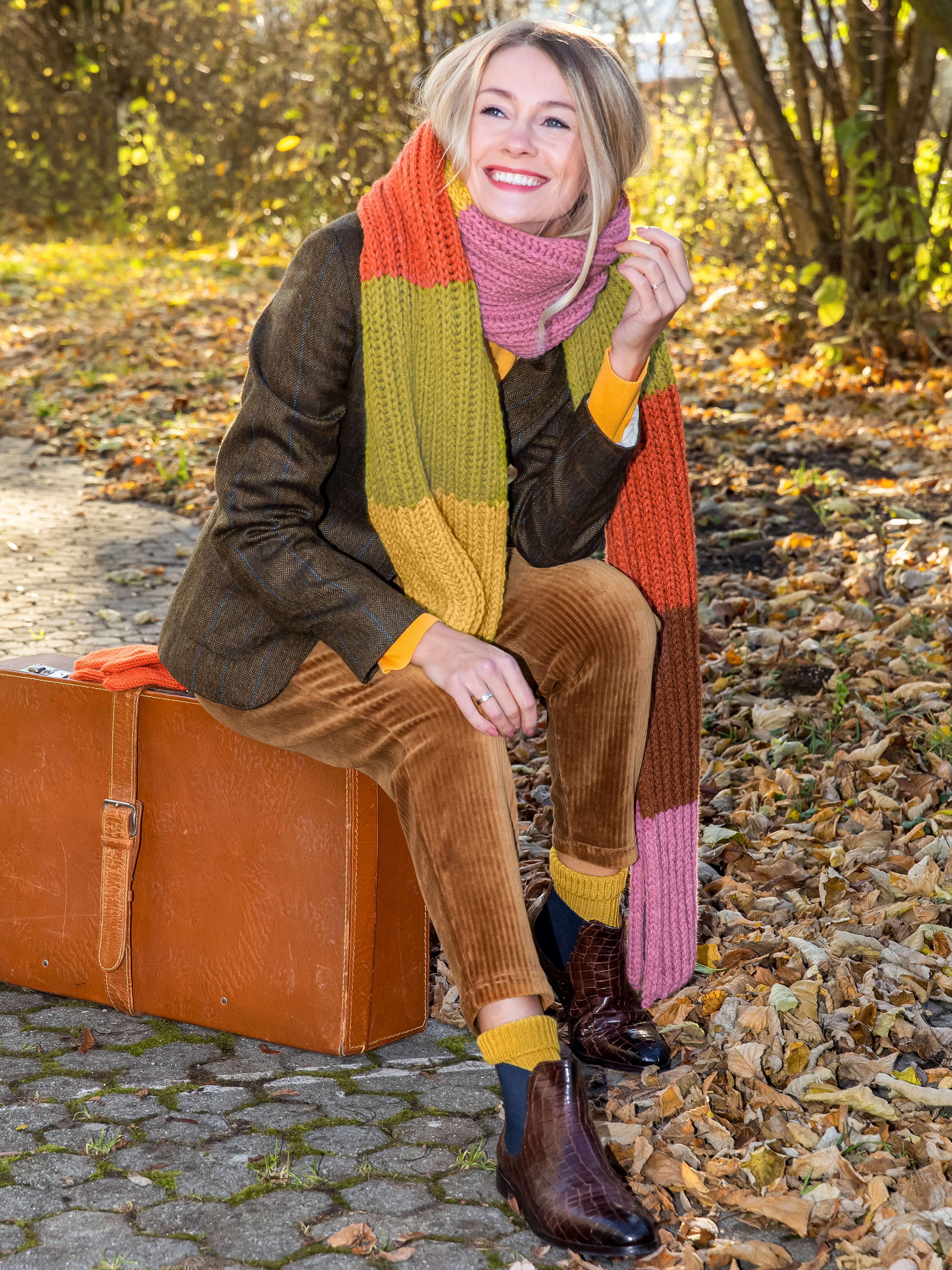 lachende blonde Frau mit buntem Schal im Herbst