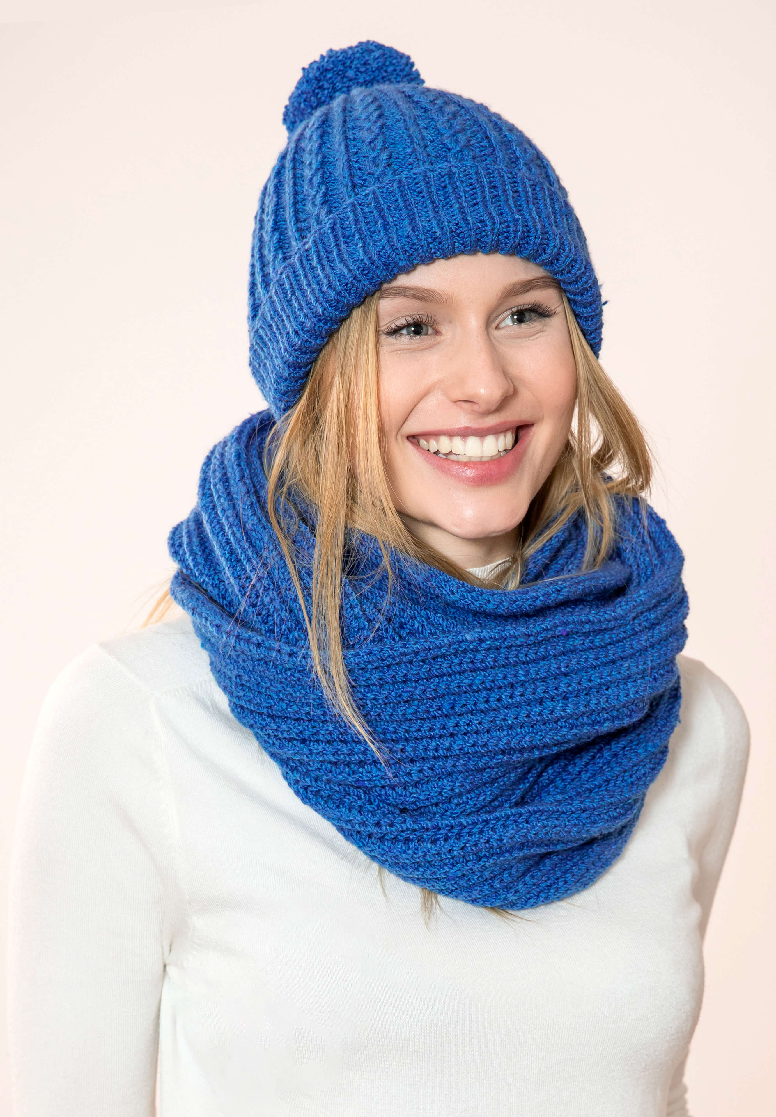 blonde lachende Frau mit blaue gestricktem Loop und Mütze