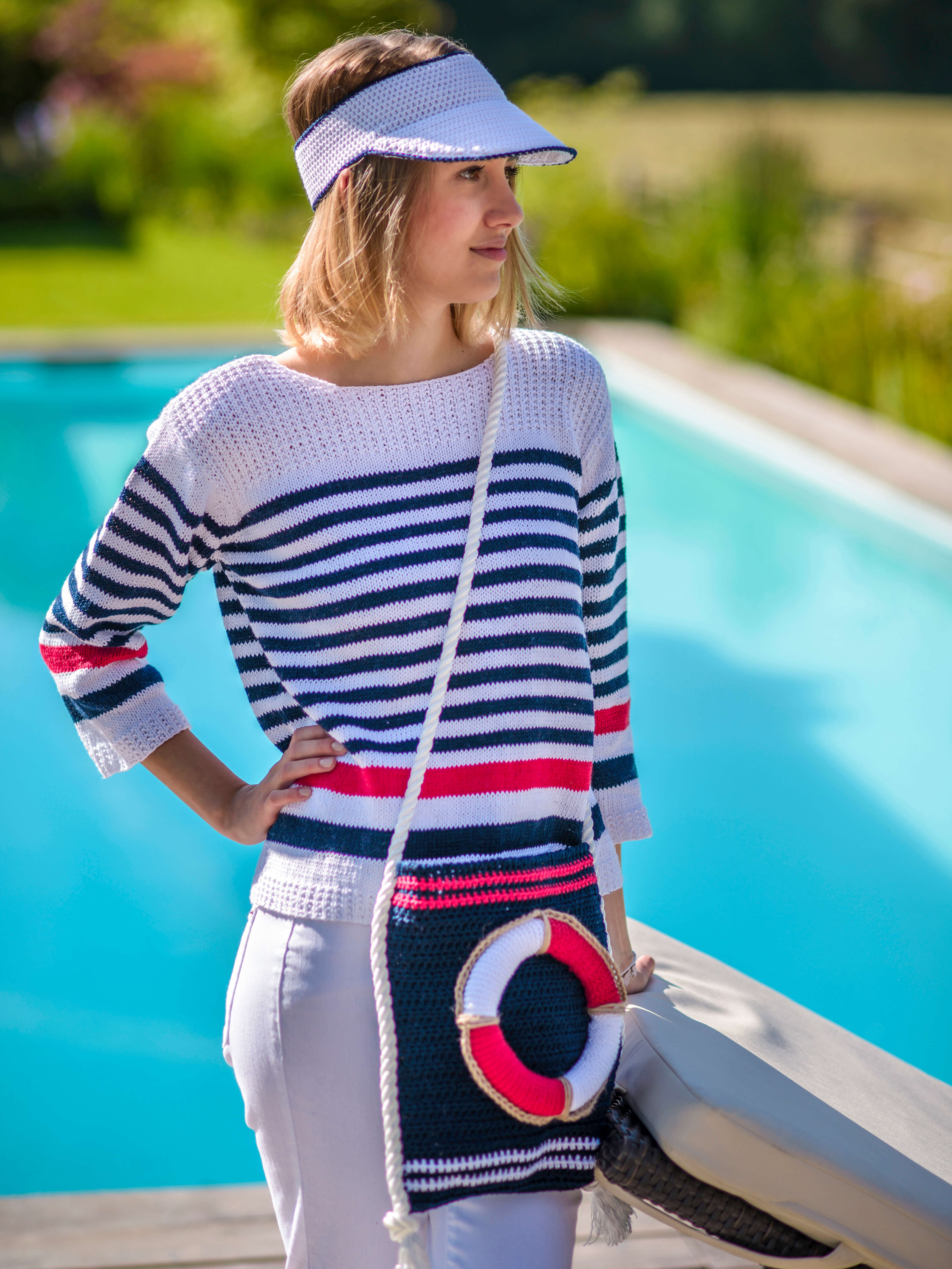 Frau am Pool mit maritimen Outfit aus gestricktem Streifenpullover und Maritimer Tascher mit Rettungsring-Applikation