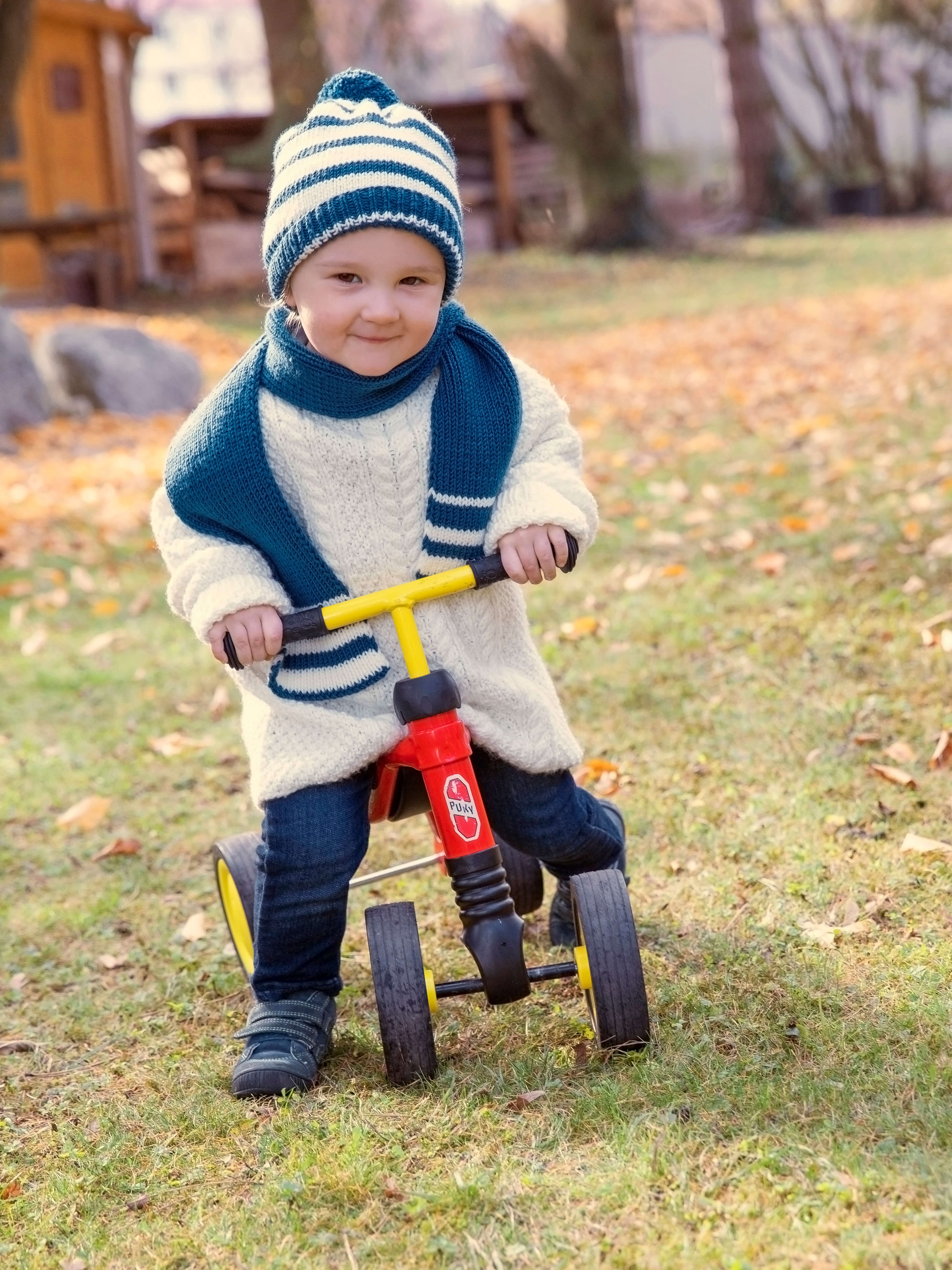 Kleiner Jung in gestricktem Pullover mit passender Mütze und Schal aus Baby color Wolle von Gründl