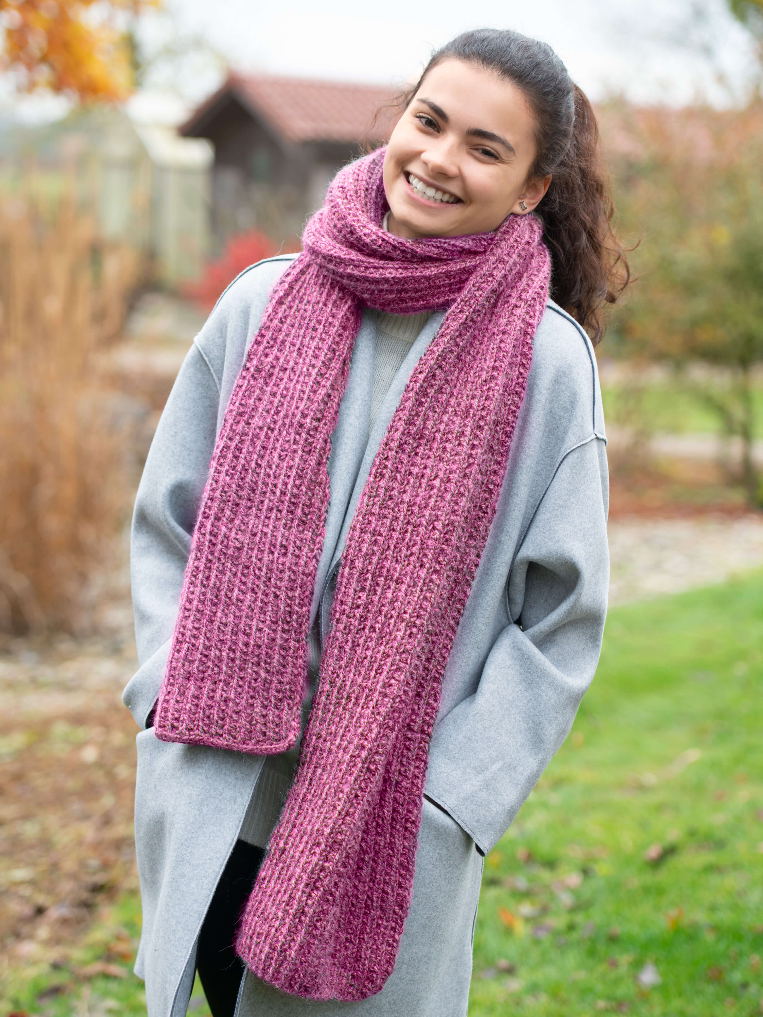 brünette lachende Frau mit pinkem Schal 